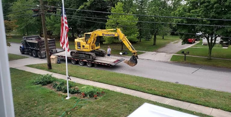 Brady excavator being delivered on a lowboy trailer for a residential job