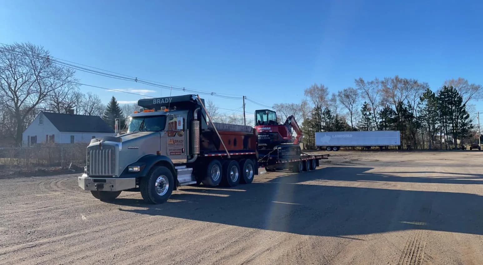 Brady Sand & Gravel Kenworth dump truck hauling a mini excavator on a flatbed trailer