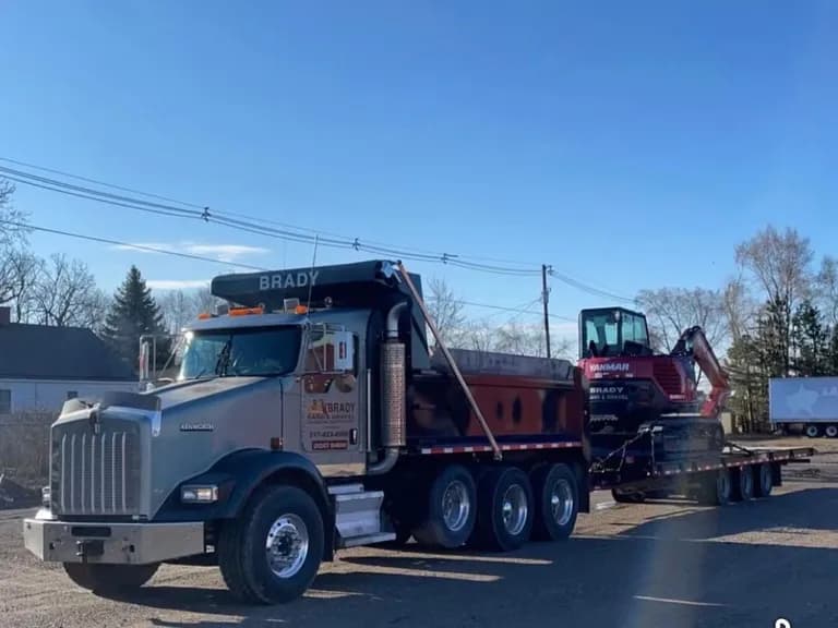 Brady Sand & Gravel Kenworth tri-axle dump truck hauling a Yanmar mini excavator on a trailer